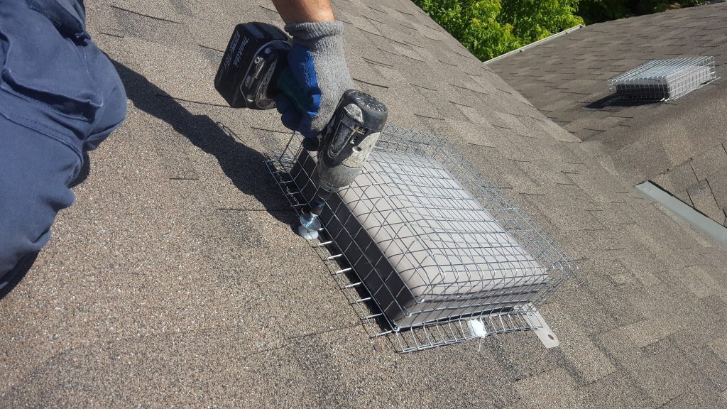 A person is working on a roof with a drill.