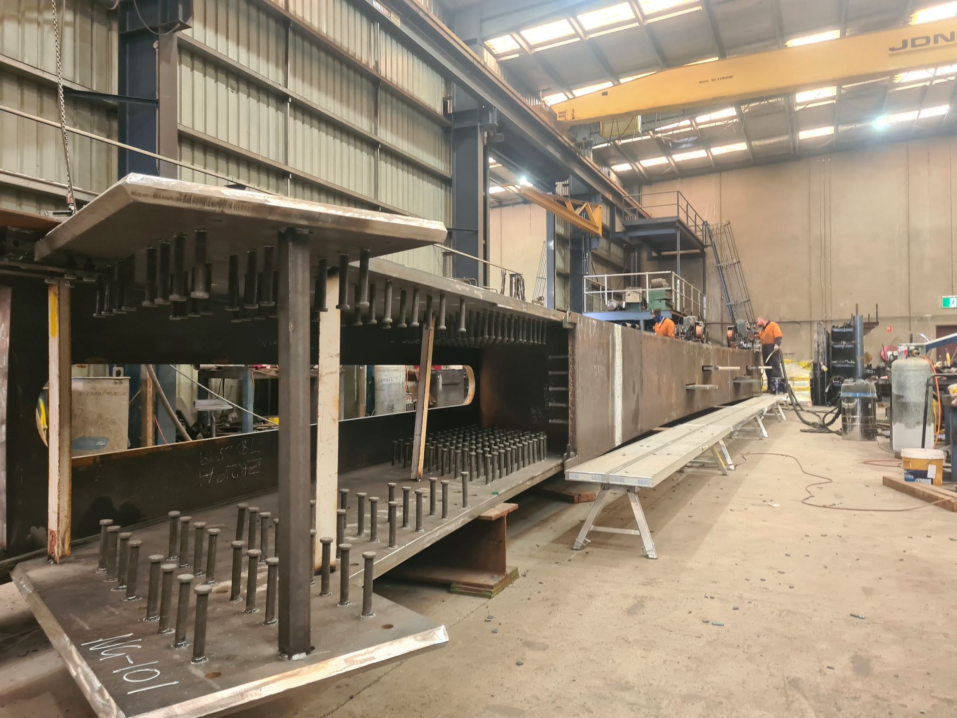 A man wearing a welding mask is welding a piece of metal.