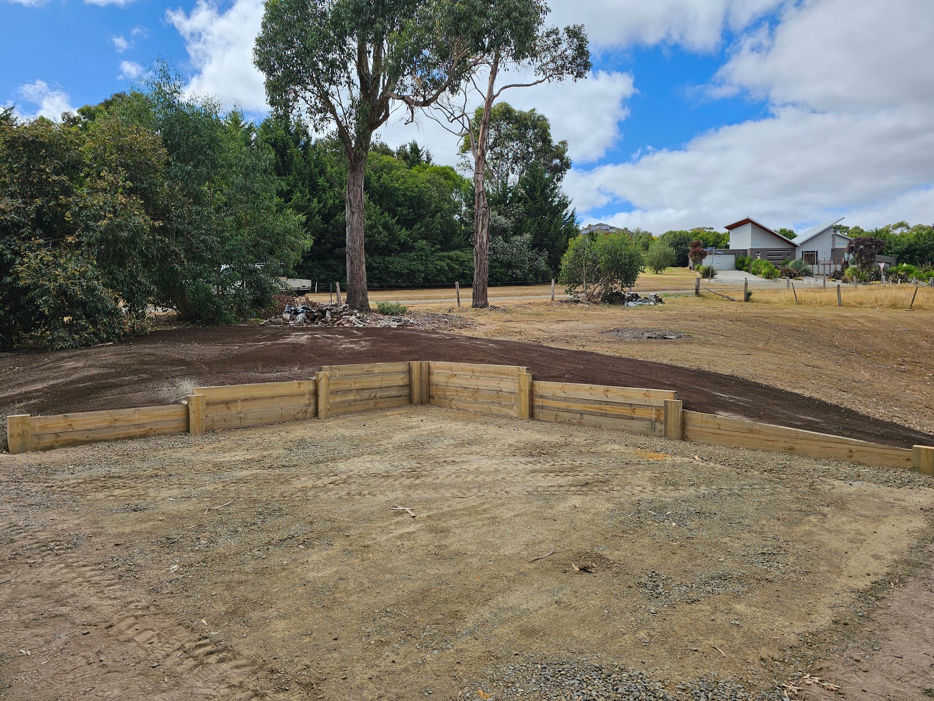 A low stone wall with built-in planters filled with green shrubs, bordering a paved area.