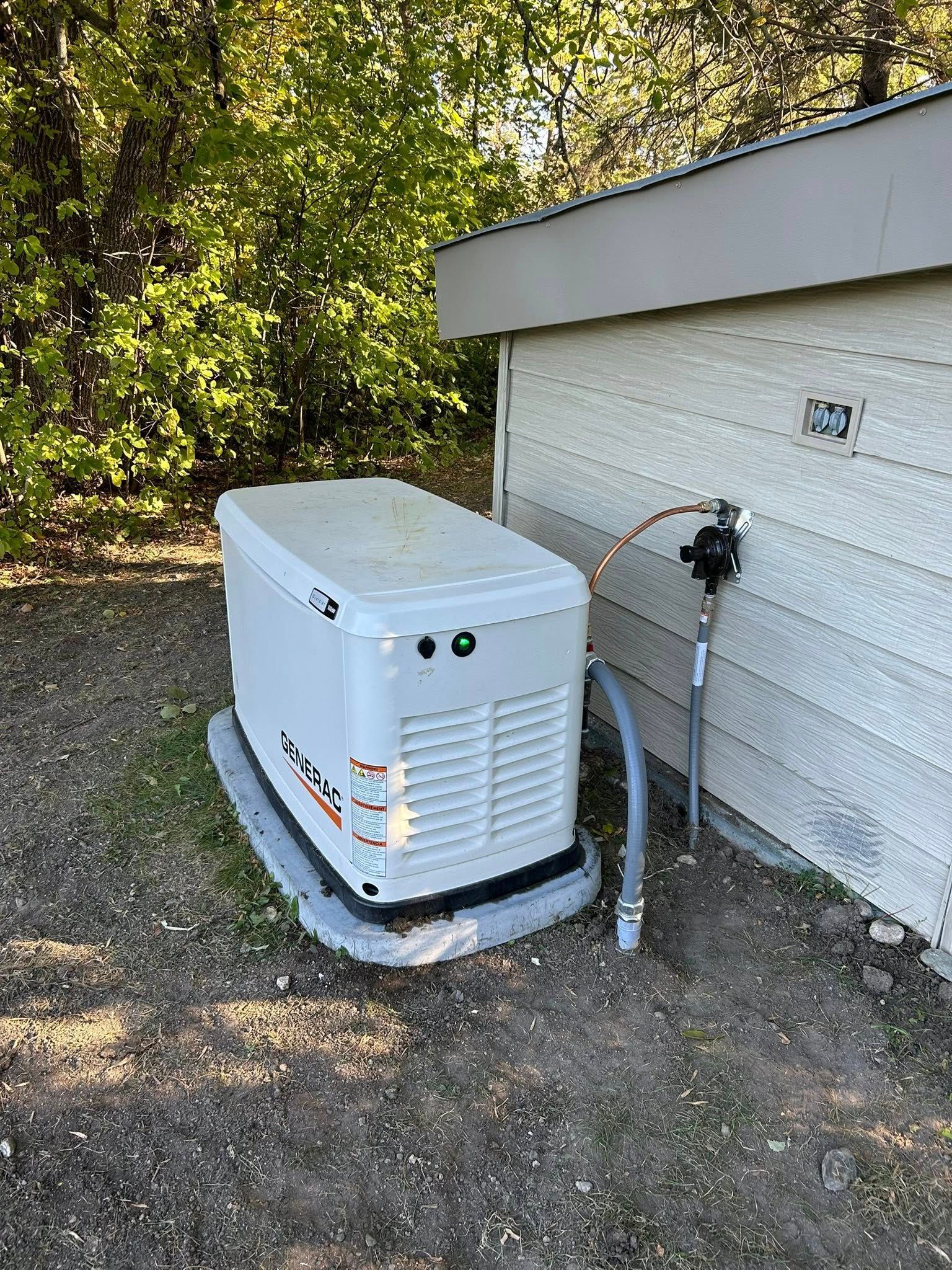 Generator next to a house with white siding and a gas line connected.