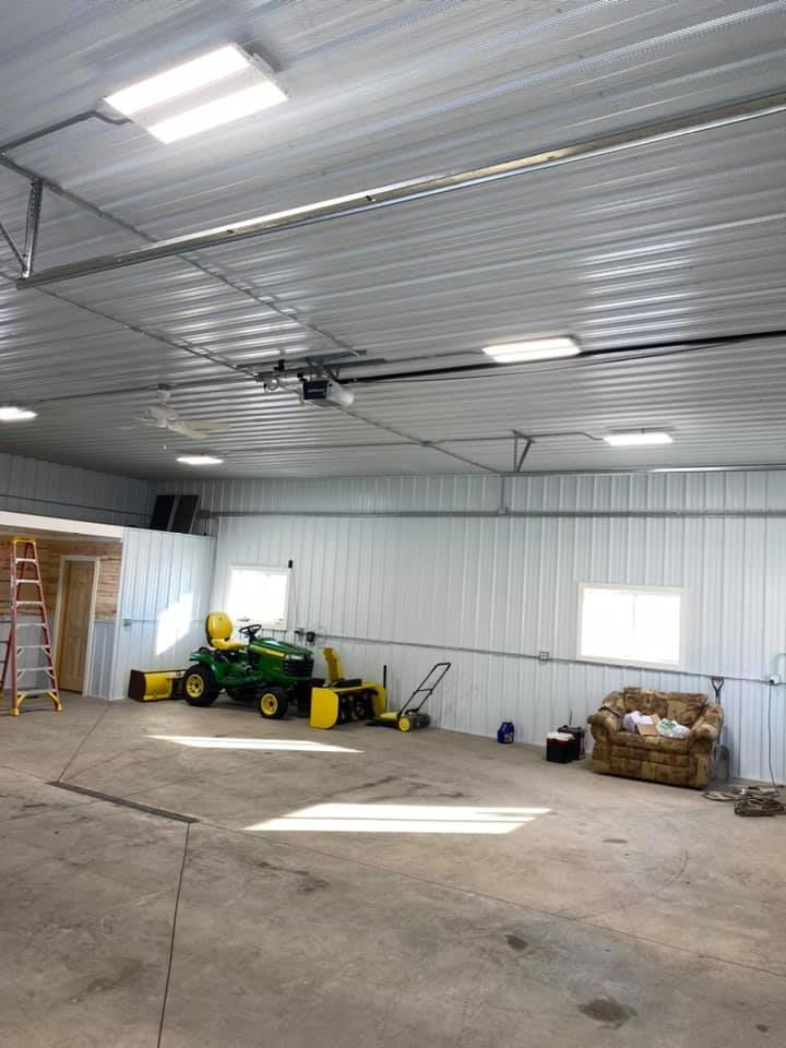 Spacious garage with a John Deere tractor, snowblower, lawnmower, and seating.