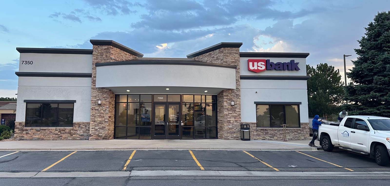 A US Bank branch in front of a cloudy sky. There is a truck parked nearby.
