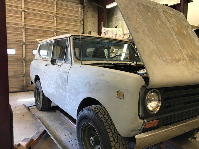 A white van with the hood up is sitting on a lift in a garage.