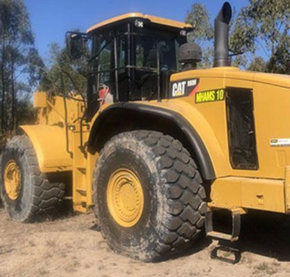A large yellow bulldozer is parked in a dirt field.