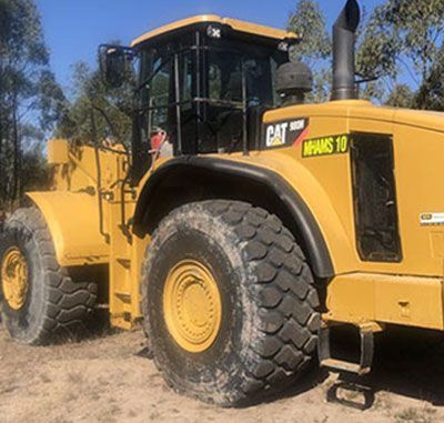 A large yellow bulldozer is parked in a dirt field.