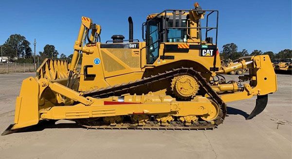 A yellow bulldozer is parked in a parking lot.