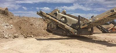 A large machine is sitting in the middle of a dirt field.