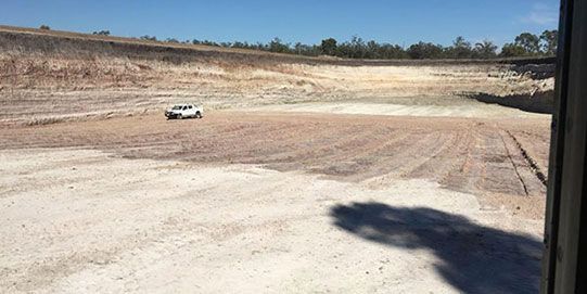 A white truck is parked in the middle of a dirt field.