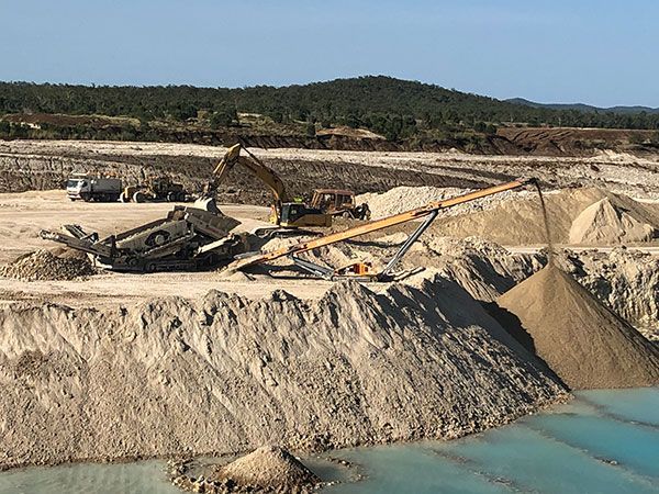 A large pile of dirt is sitting next to a body of water.