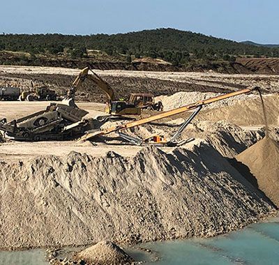 A large pile of dirt is being dumped into a body of water.
