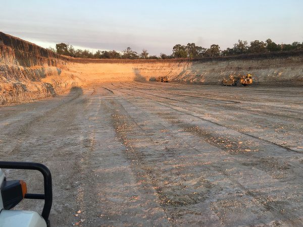 A tractor is driving down a dirt road in a quarry.