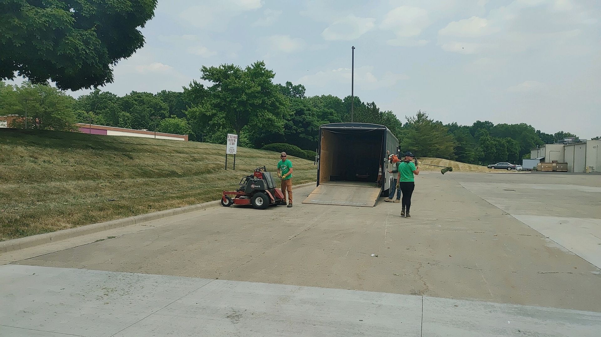 A truck is sitting on the side of the road next to a lawn mower.