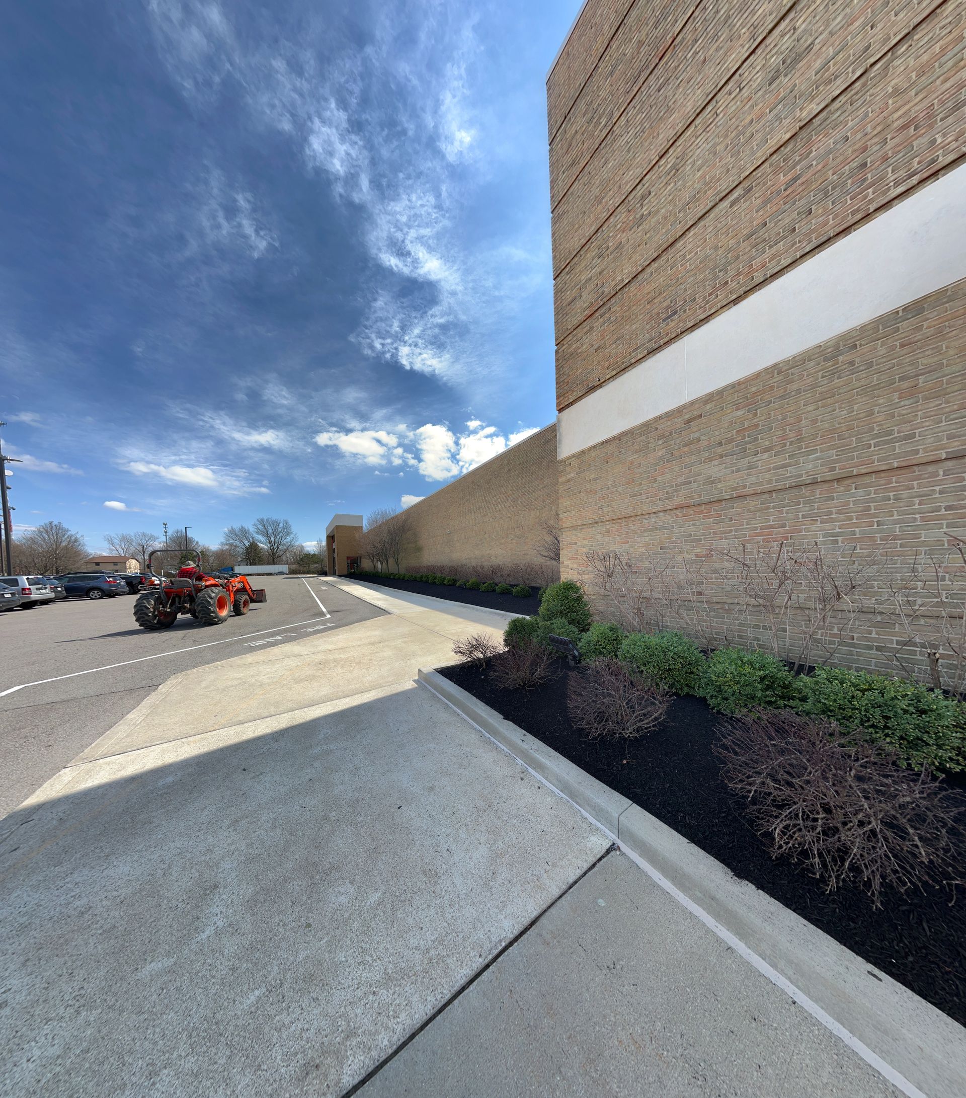 A tractor is parked in a parking lot next to a building.