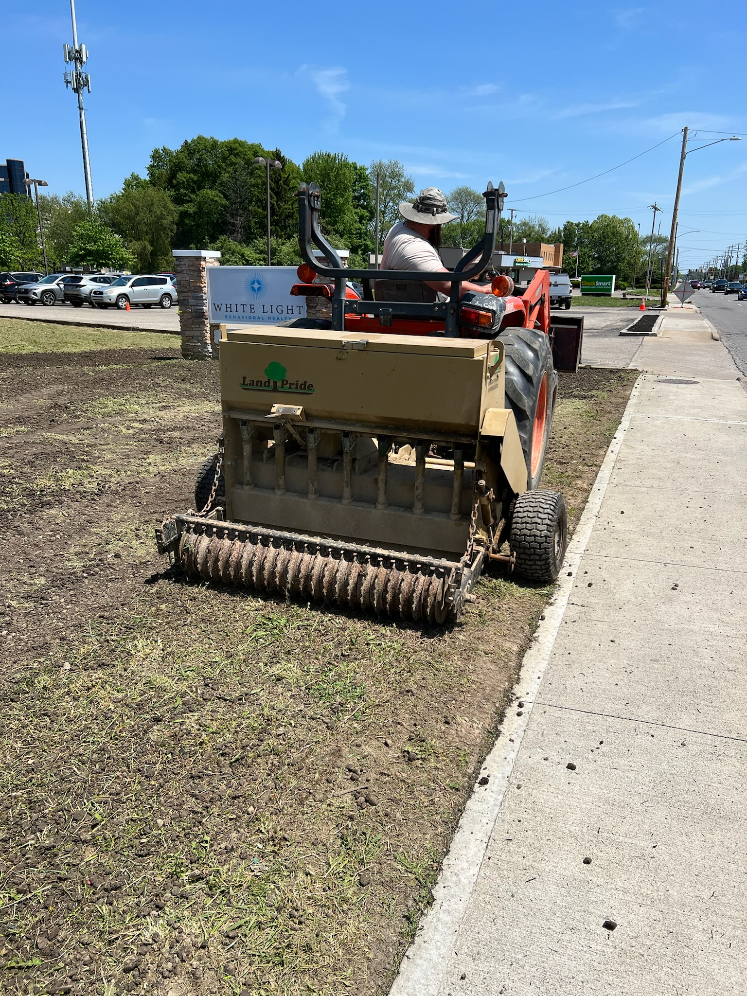 A man is driving a tractor down a sidewalk.