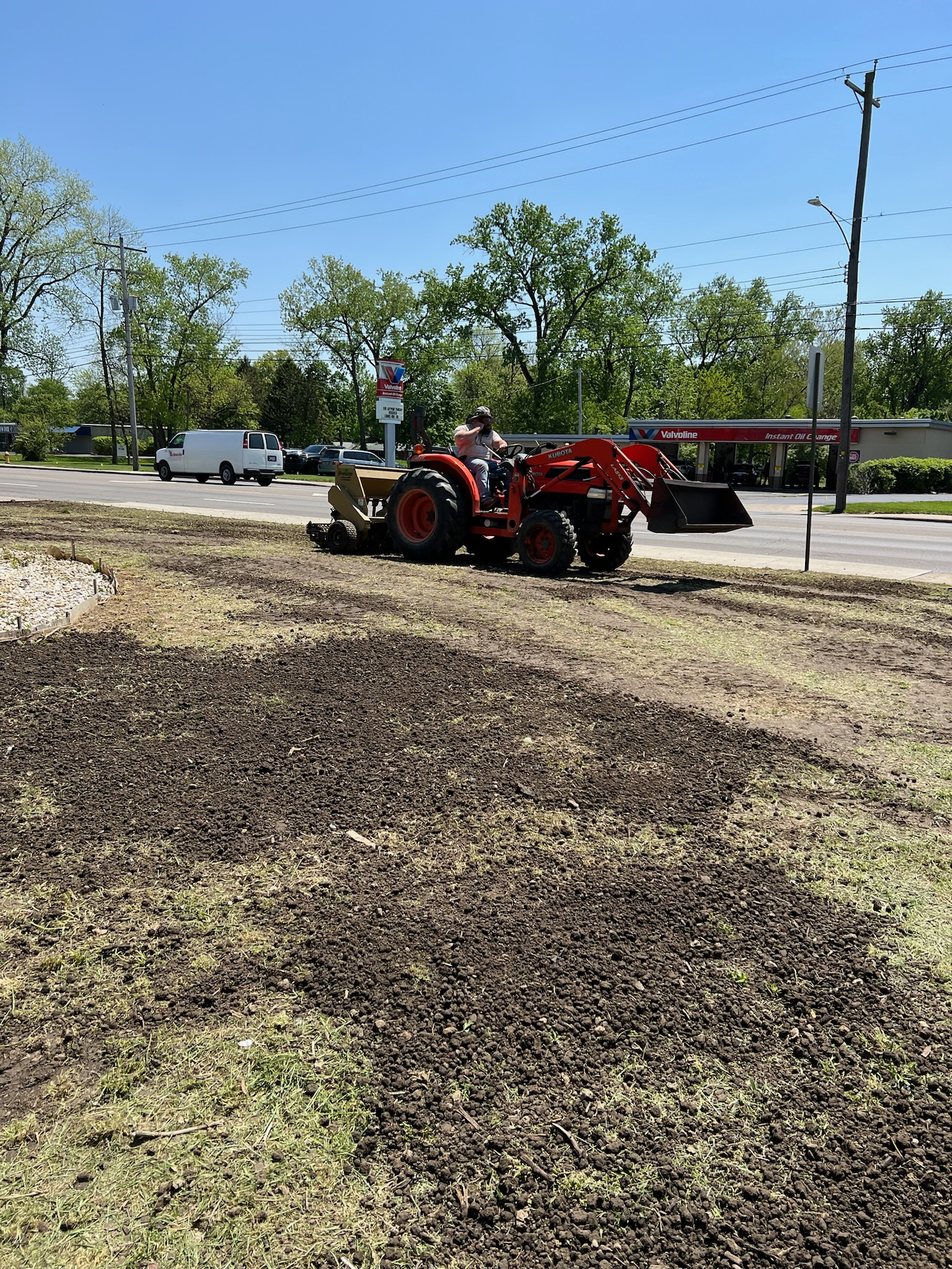A red tractor is plowing a field of dirt.