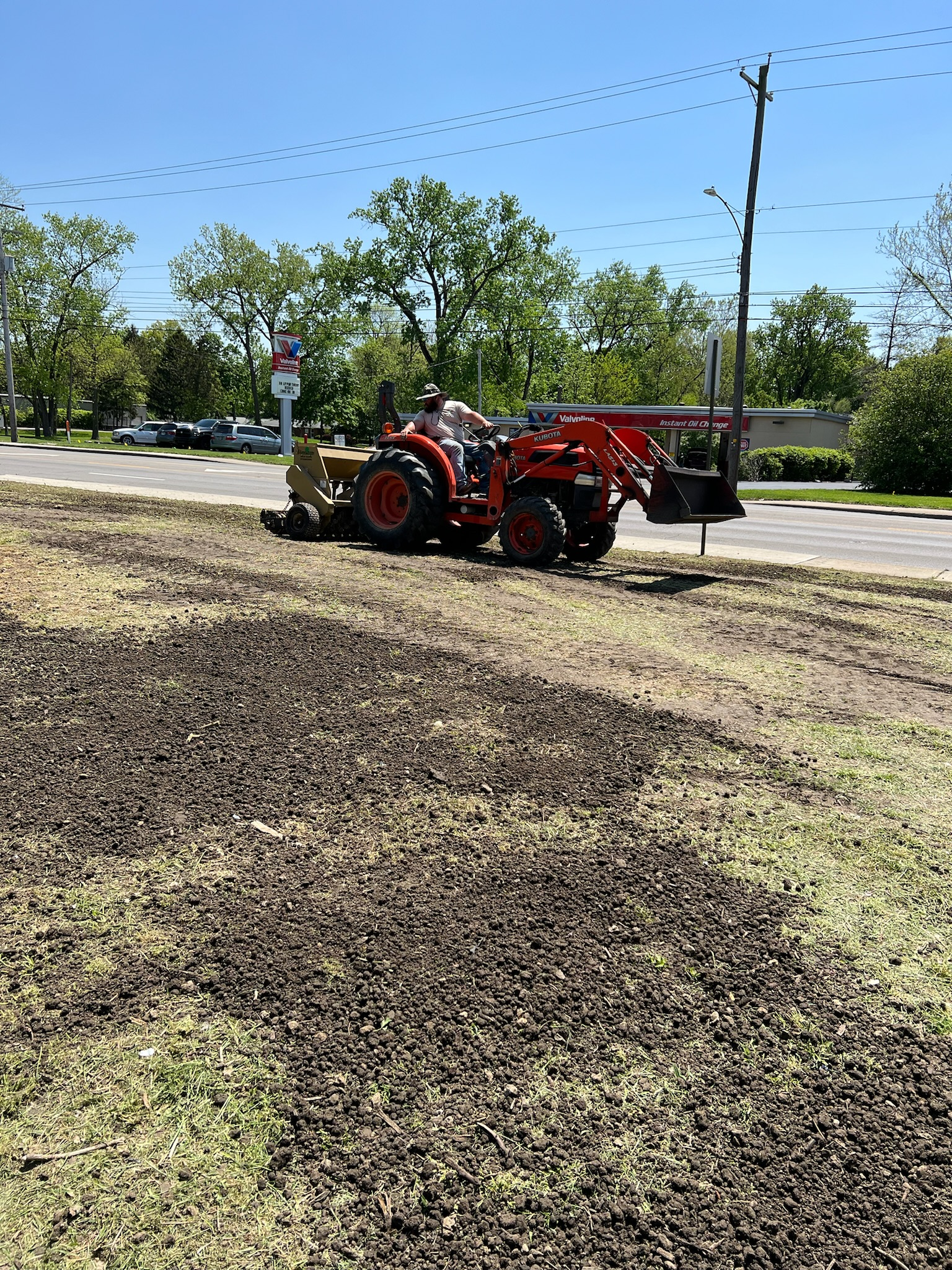 A tractor is plowing a field next to a road.