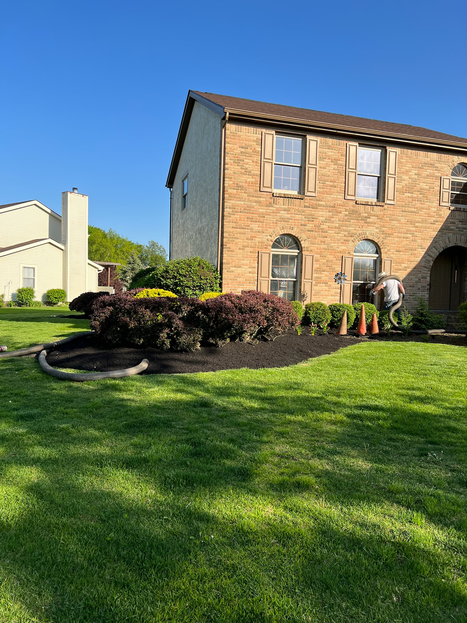 A large brick house with a lush green lawn in front of it.
