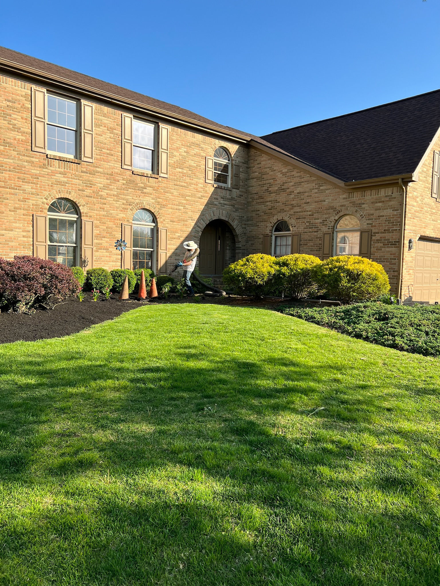 A large brick house with a lush green lawn in front of it.