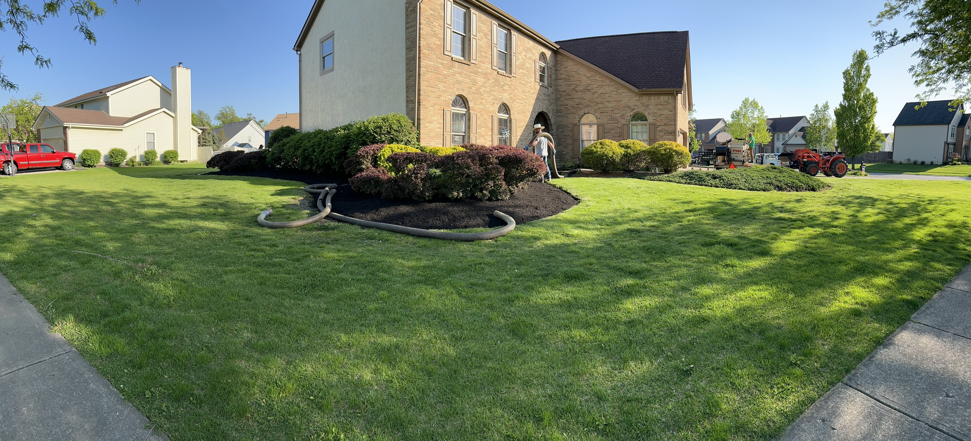 A large brick house with a lush green lawn in front of it.
