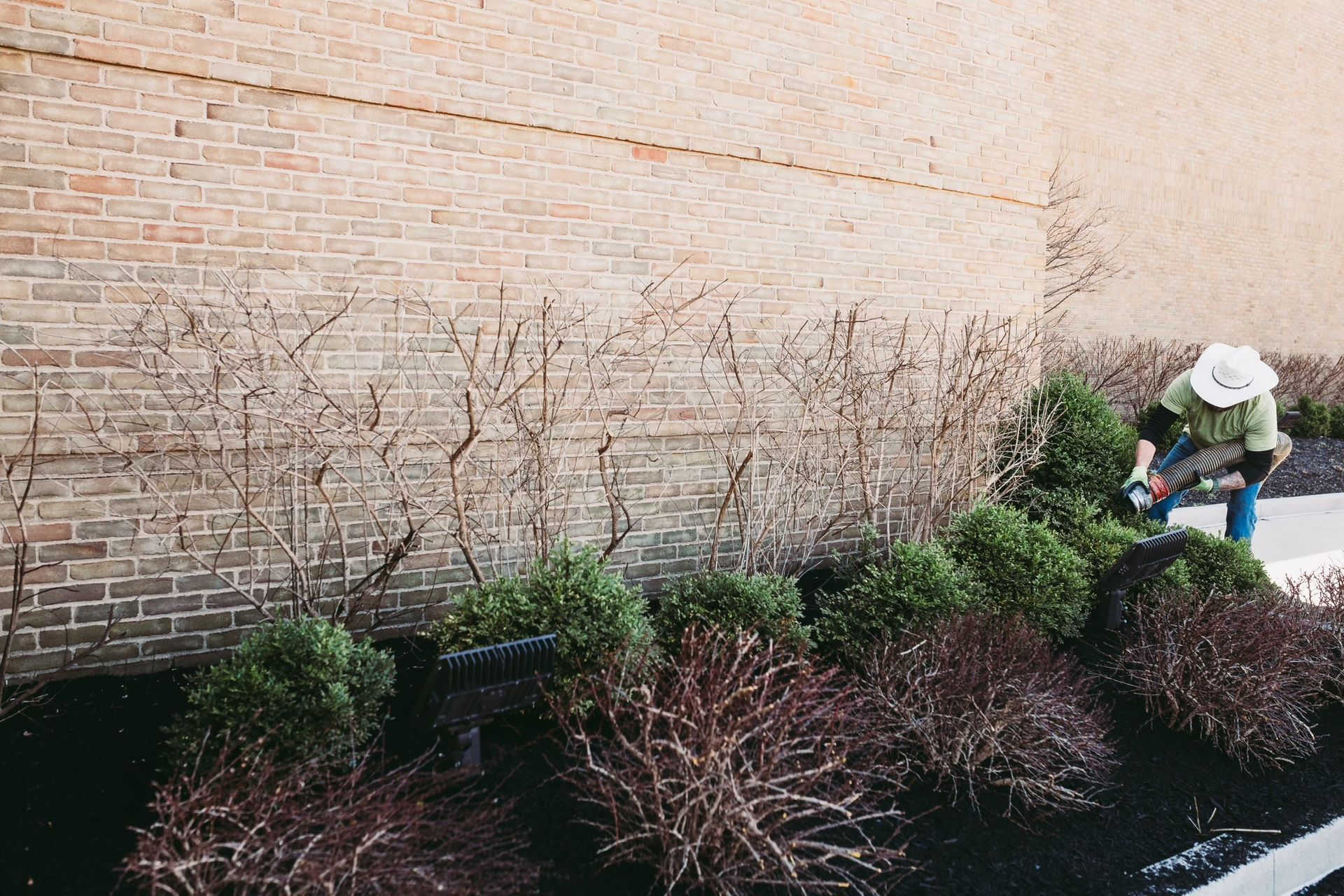 A person is kneeling down in front of a brick wall.