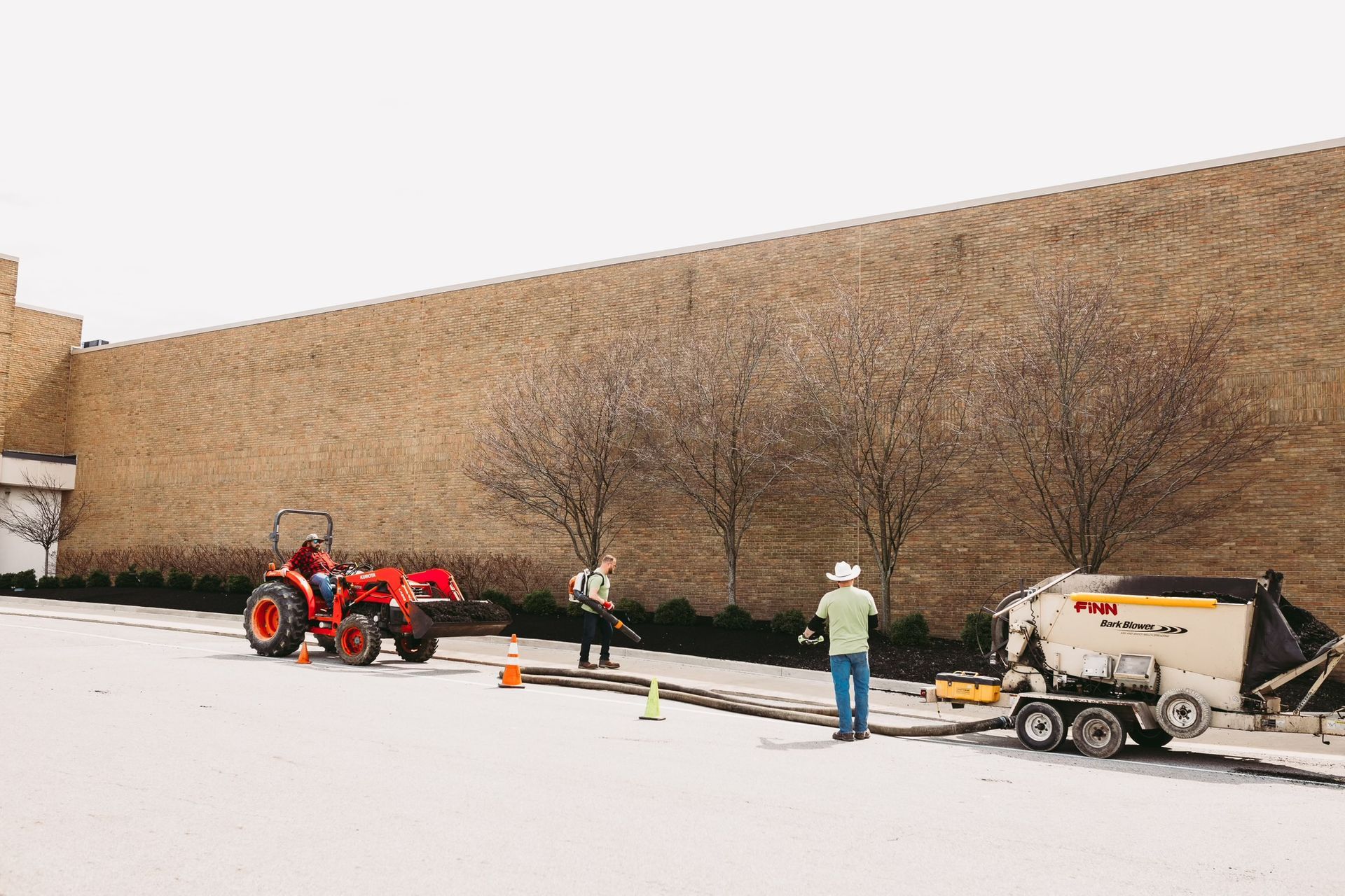 A man is standing next to a tractor in a parking lot.