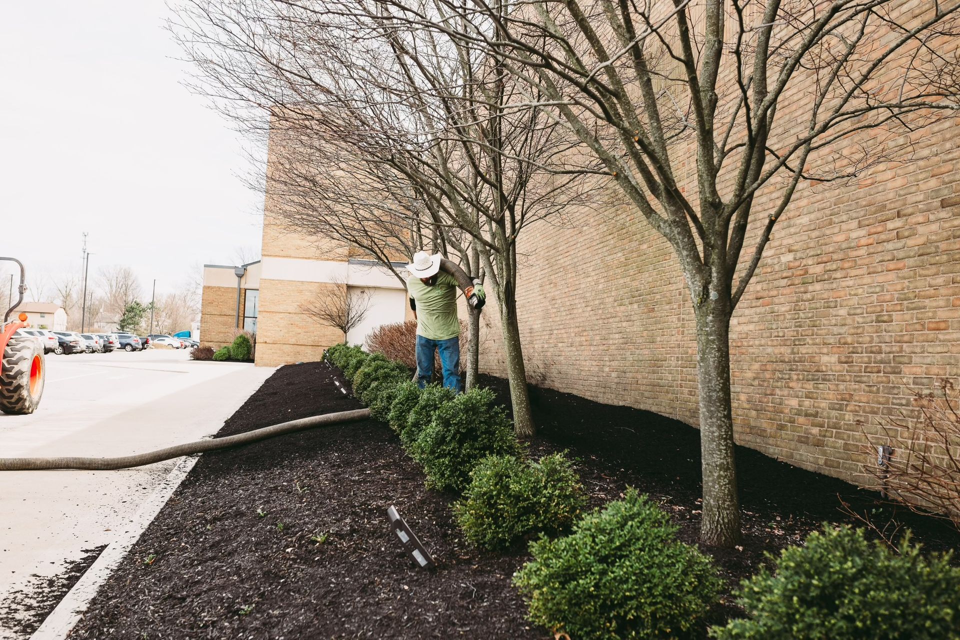 A man is standing in a garden next to a brick building.