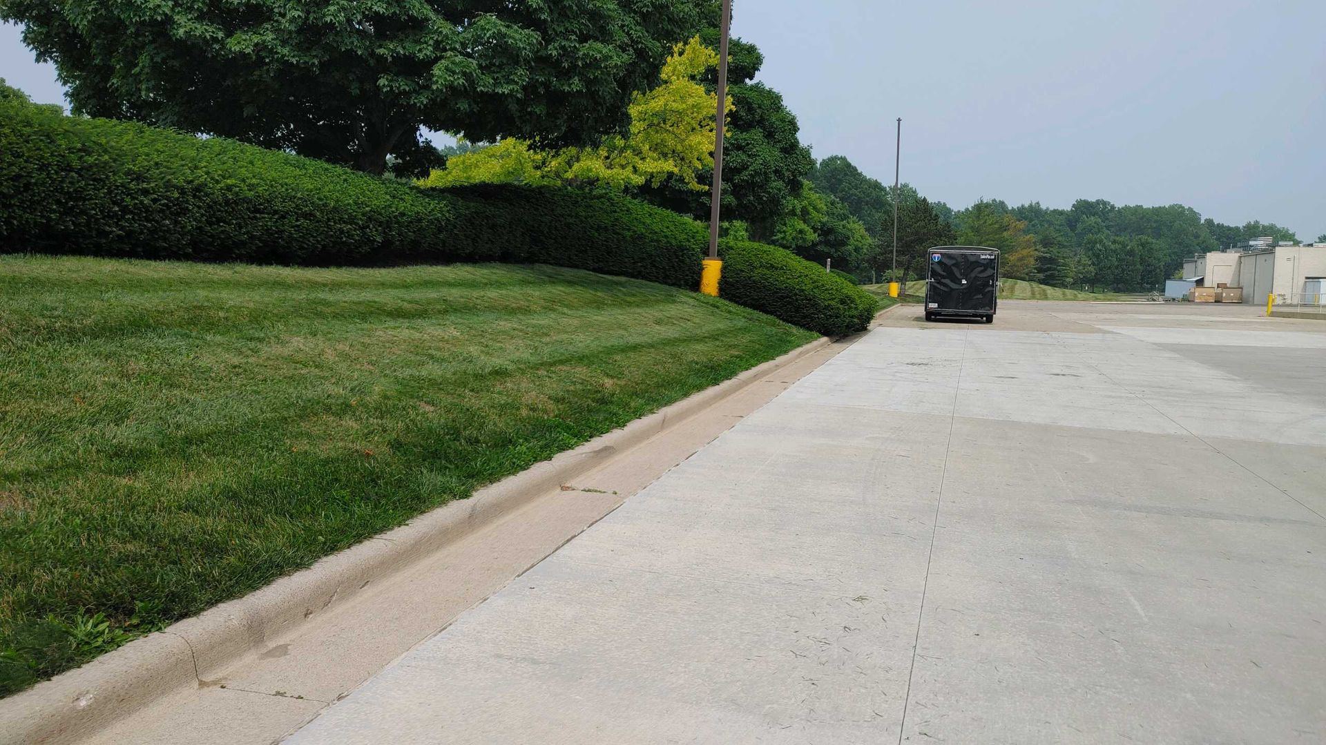 A car is parked on the side of a road next to a lush green field.