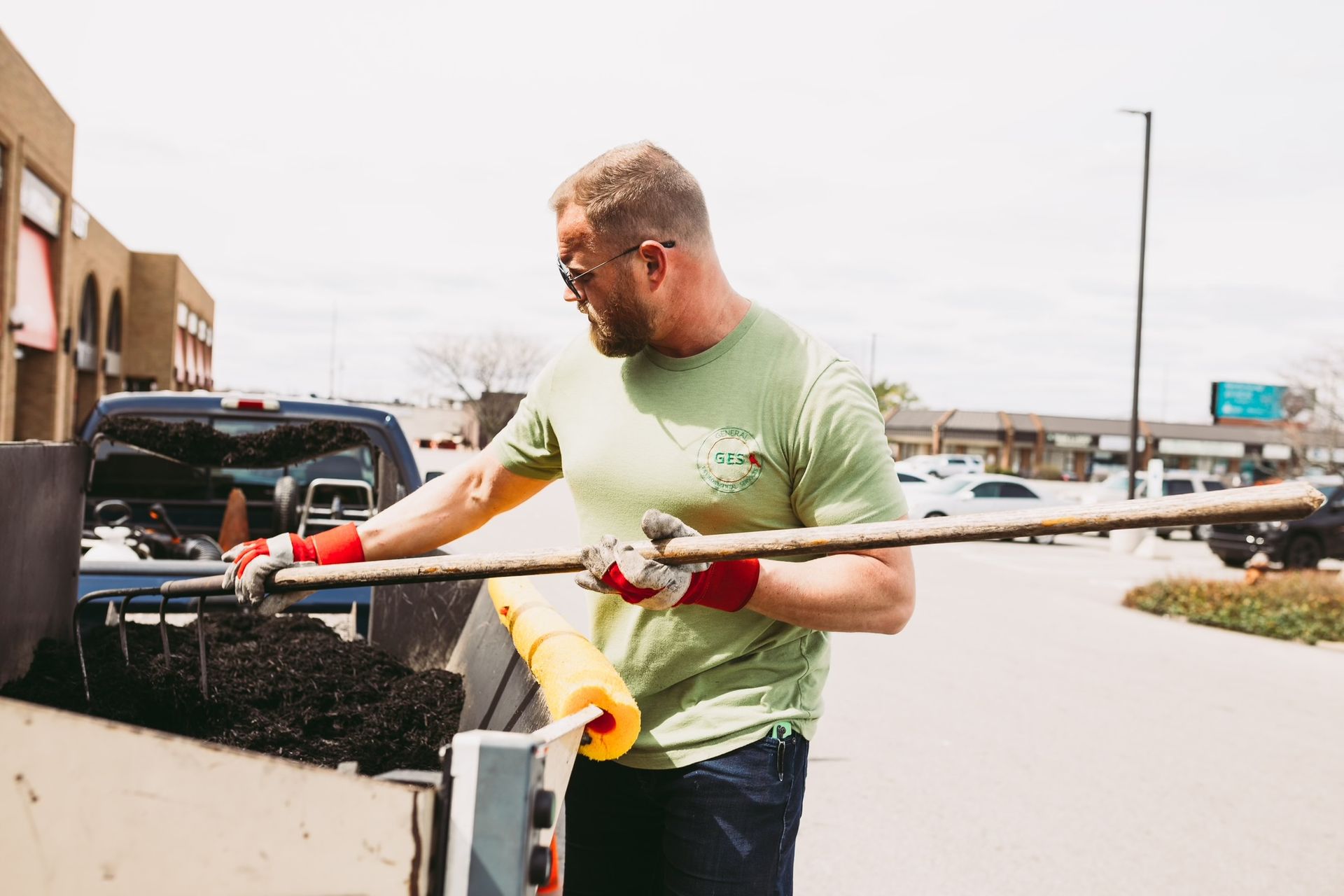 A man in a green shirt is holding a larget tool in his hand.