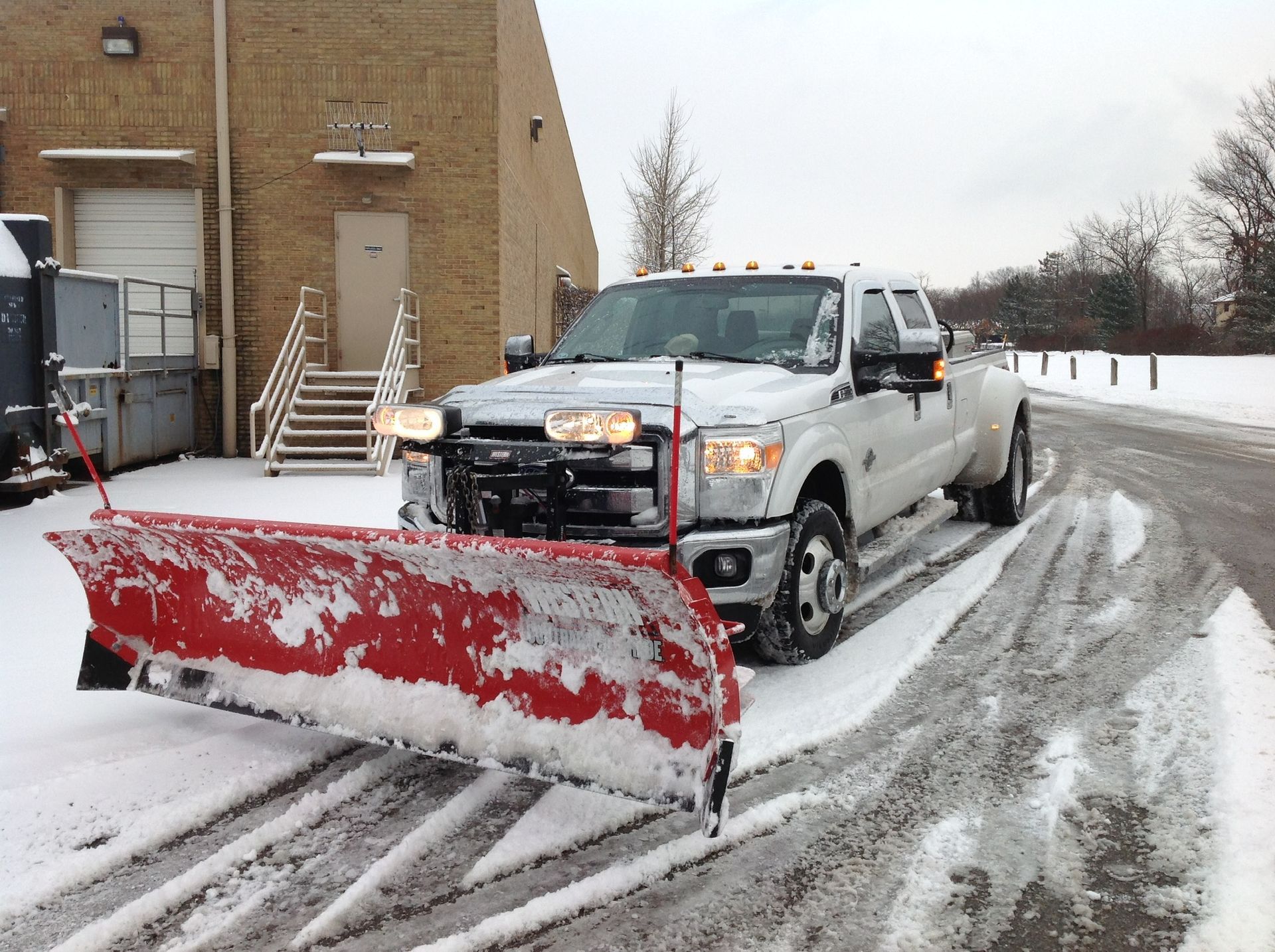 A white truck with a red snow plow attached to it