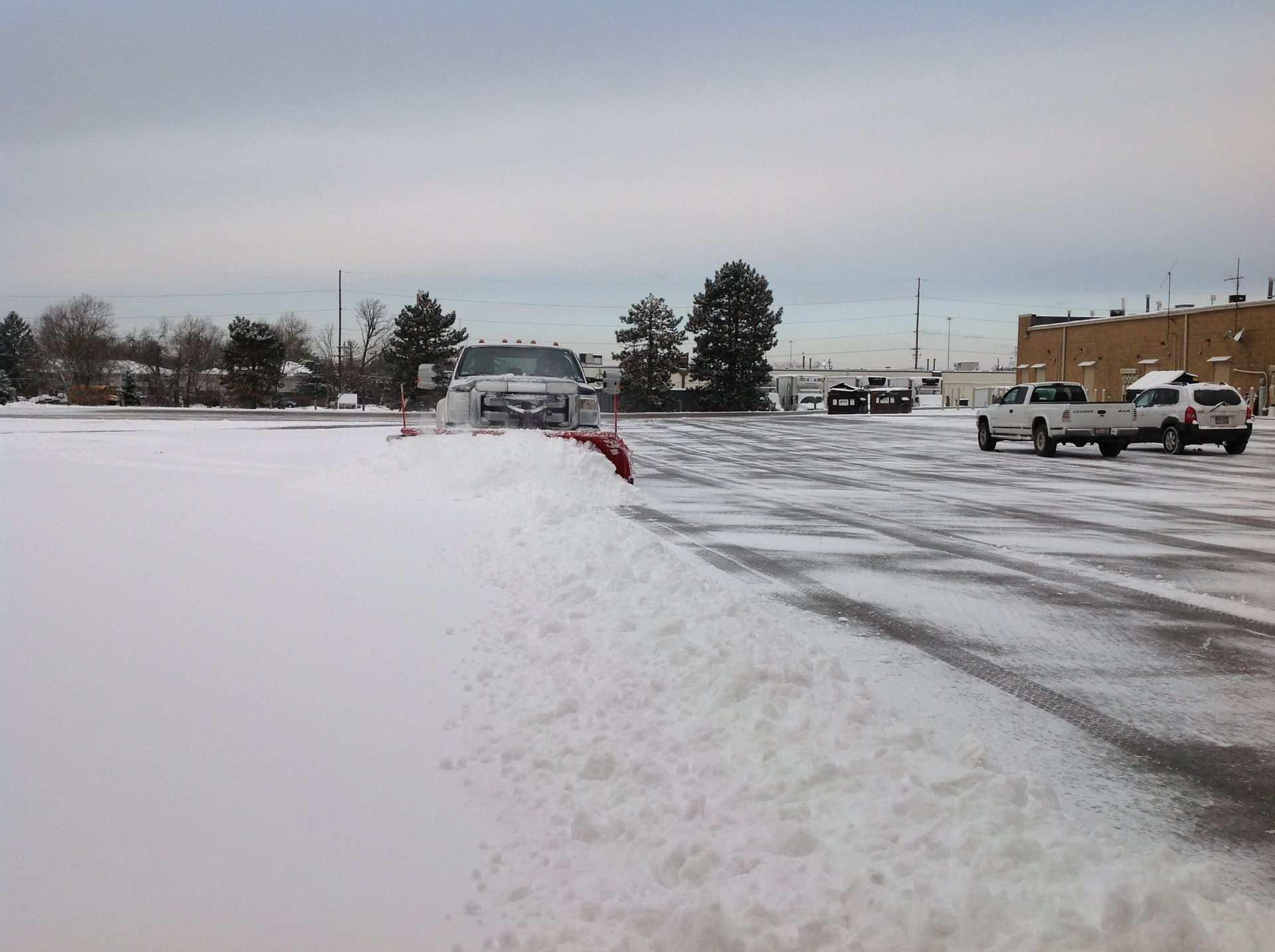 A snow plow is clearing snow from a parking lot