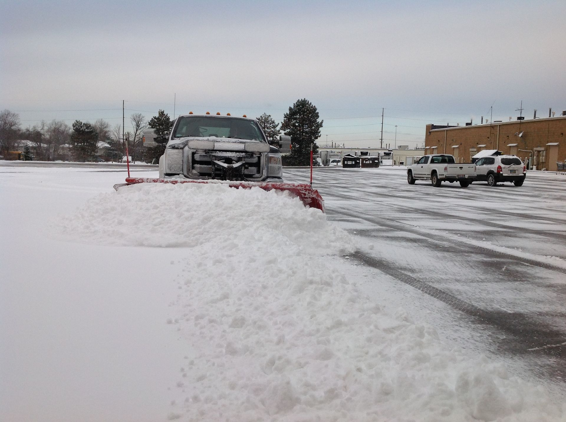 A snow plow is clearing snow from a parking lot