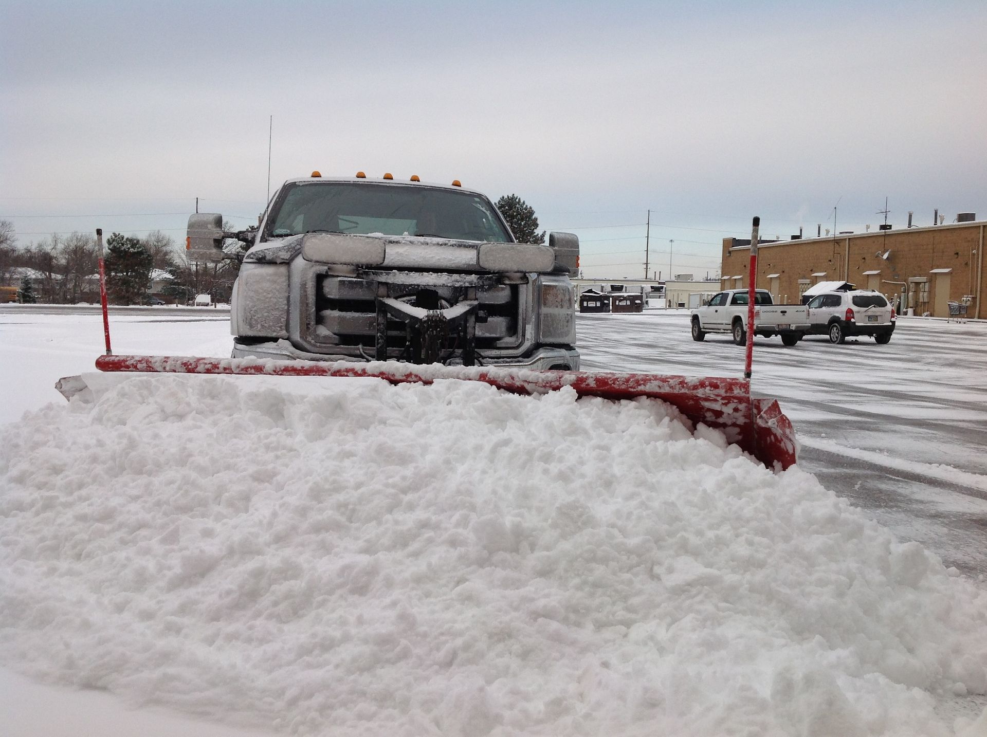 A truck is plowing snow in a parking lot