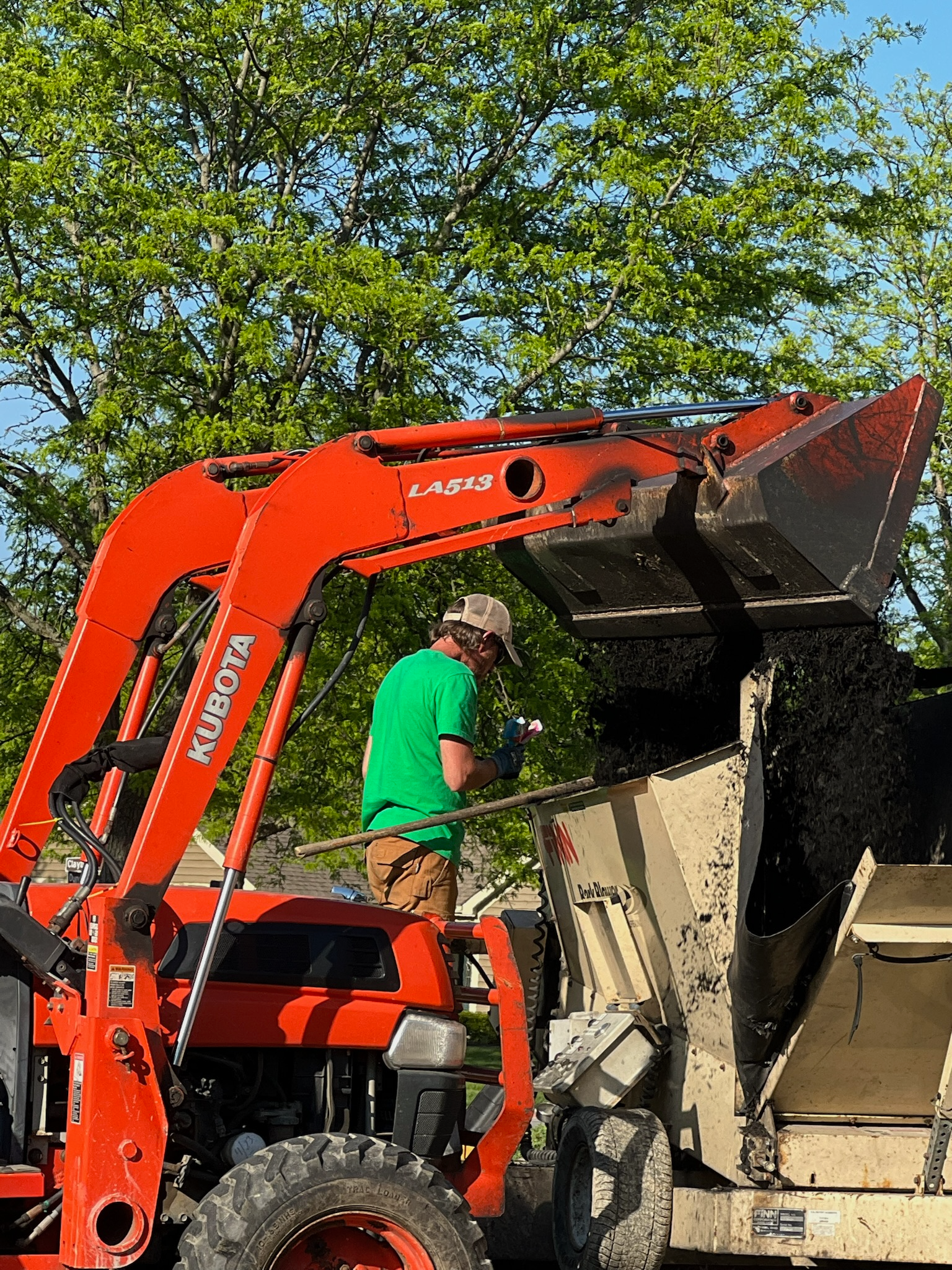 A man is riding a tractor with a bucket full of dirt.