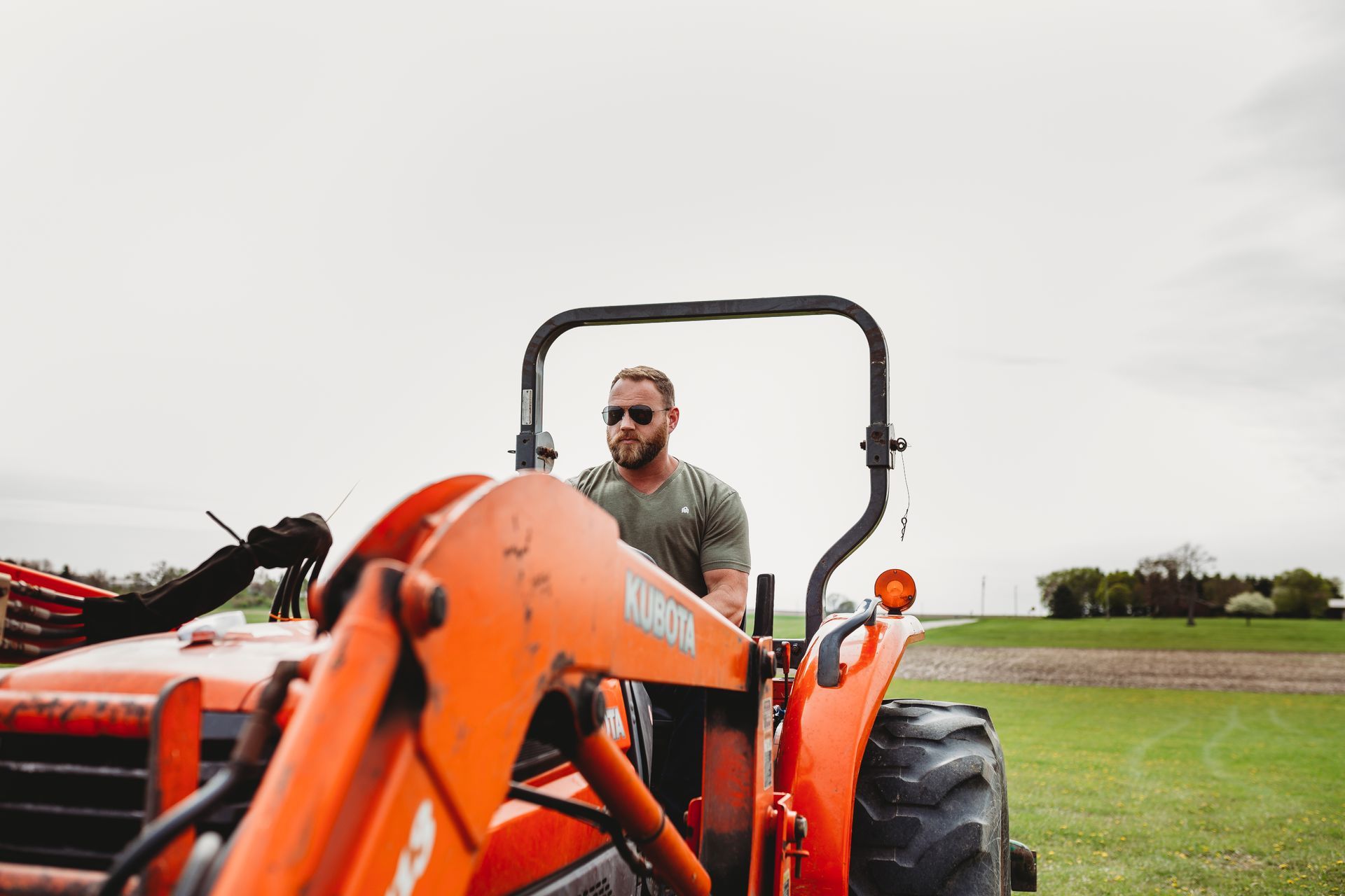 A man is driving an orange tractor in a field.