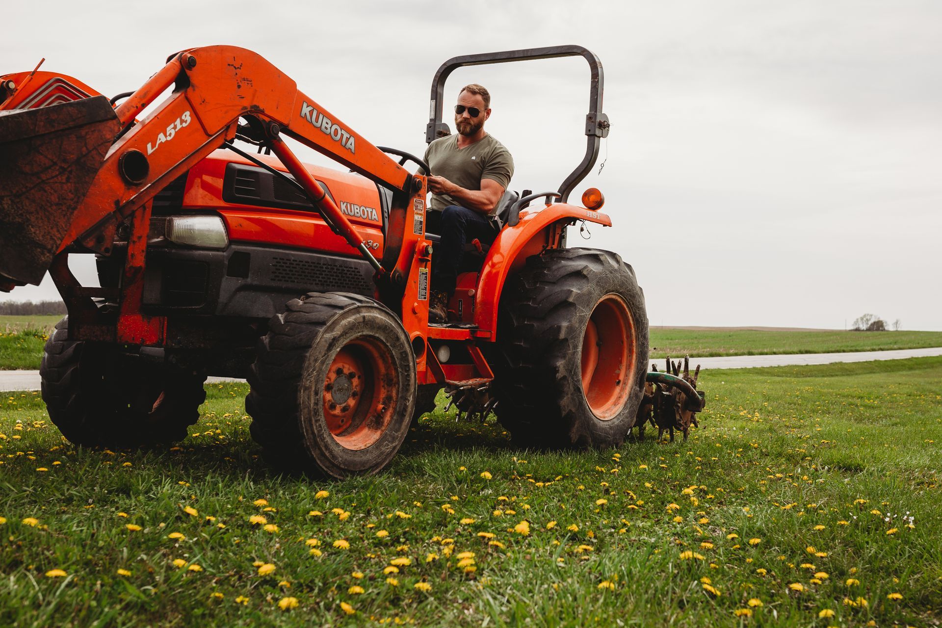 A man is sitting on a tractor in a field.