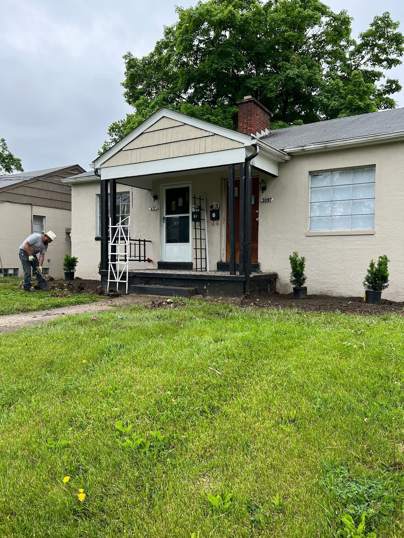 A man is standing in the grass in front of a house.