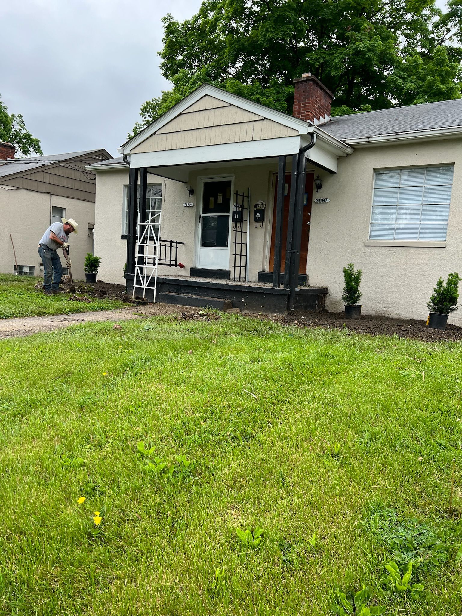 A man is standing in front of a house with a ladder.