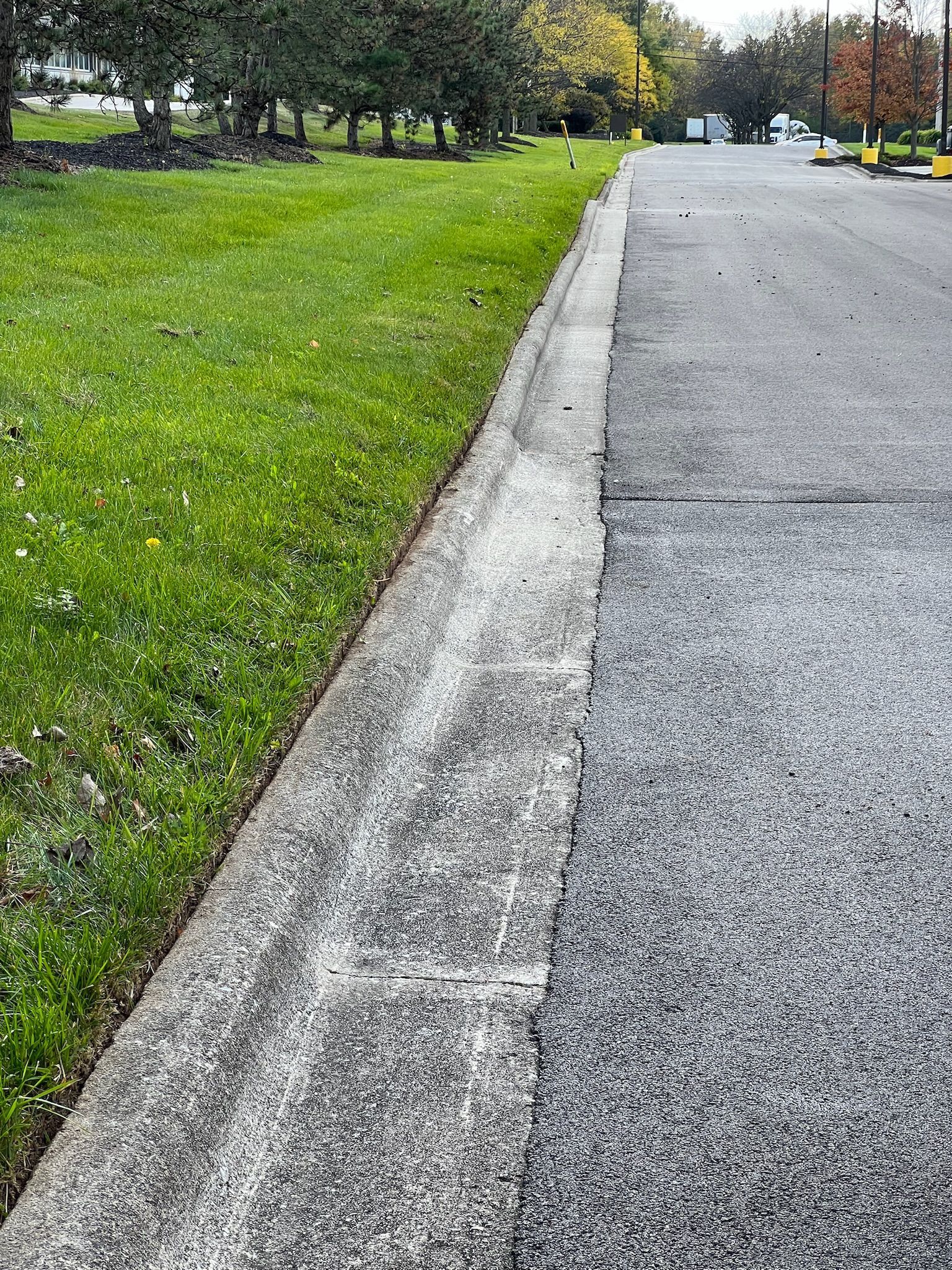 A concrete curb along a road next to a grassy field.