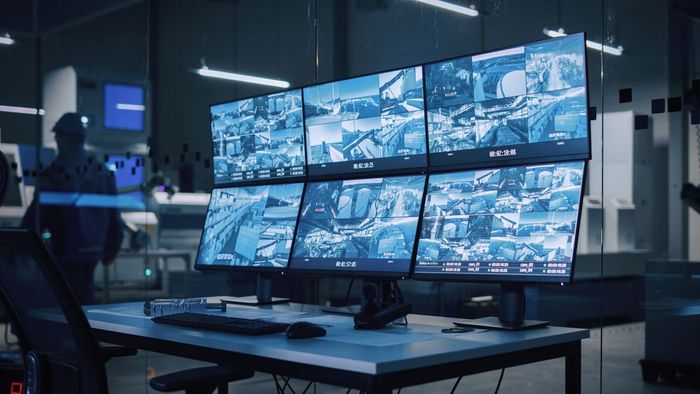 A desk with a bunch of monitors on it in a dark room.