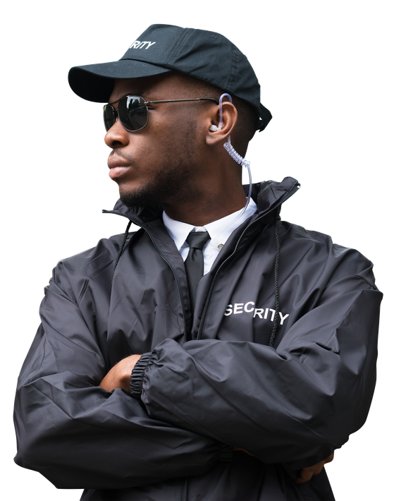 A security guard wearing a hat and sunglasses is standing with his arms crossed.