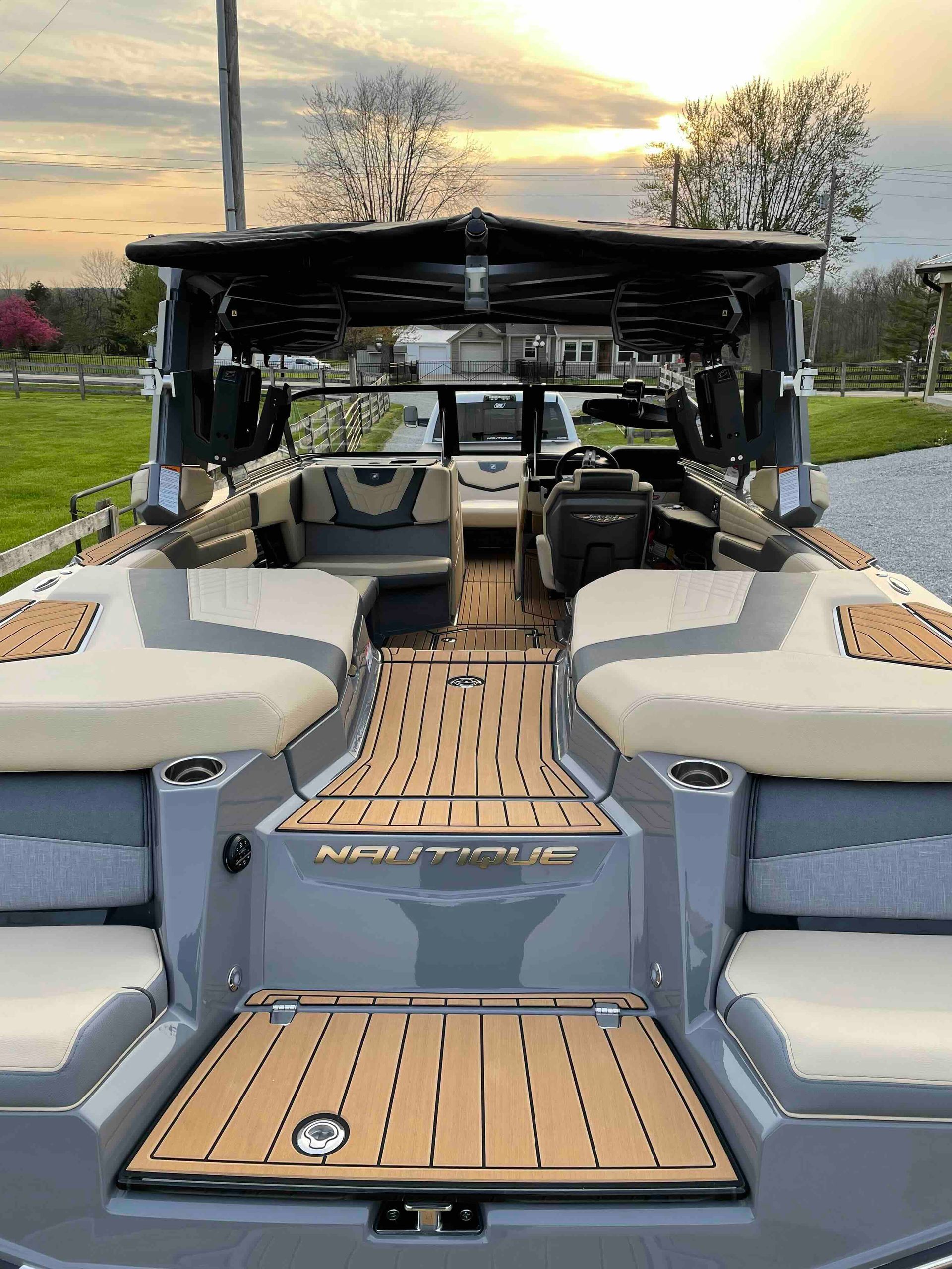 Modern motorboat interior with gray and tan seats, wooden floor, and black canopy.