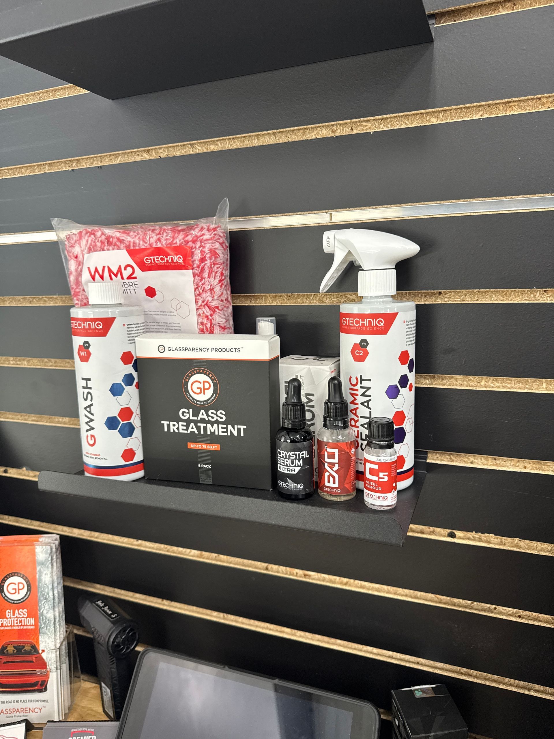 Car detailing products on a shelf: wash, sealant, glass treatment, and microfibers.