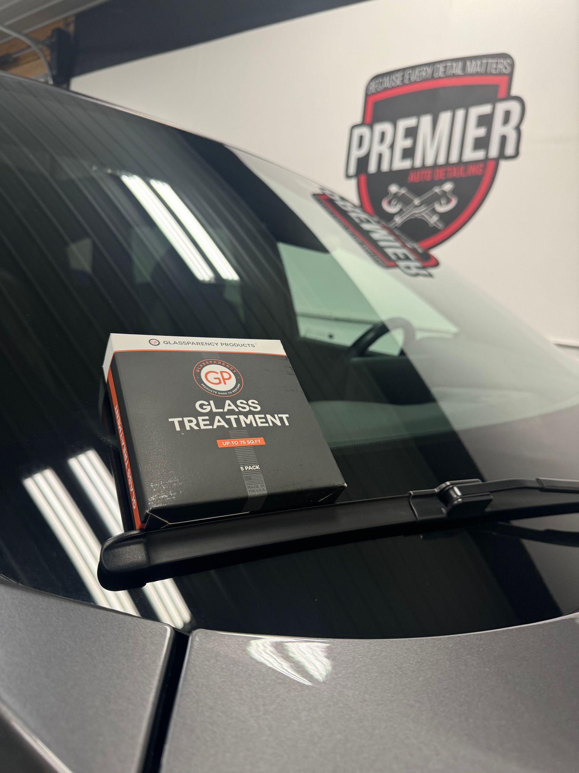 Box of glass treatment on a car windshield, with a Premier logo in the background.
