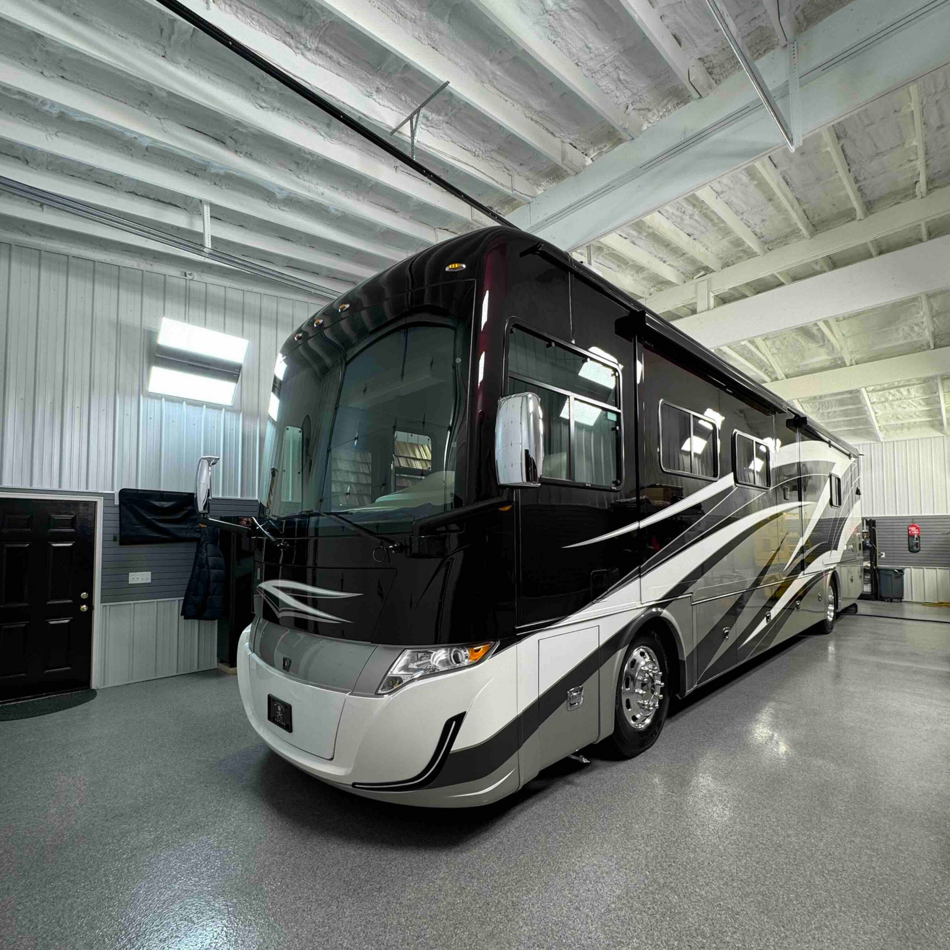 Black and silver recreational vehicle parked inside a large, white garage.