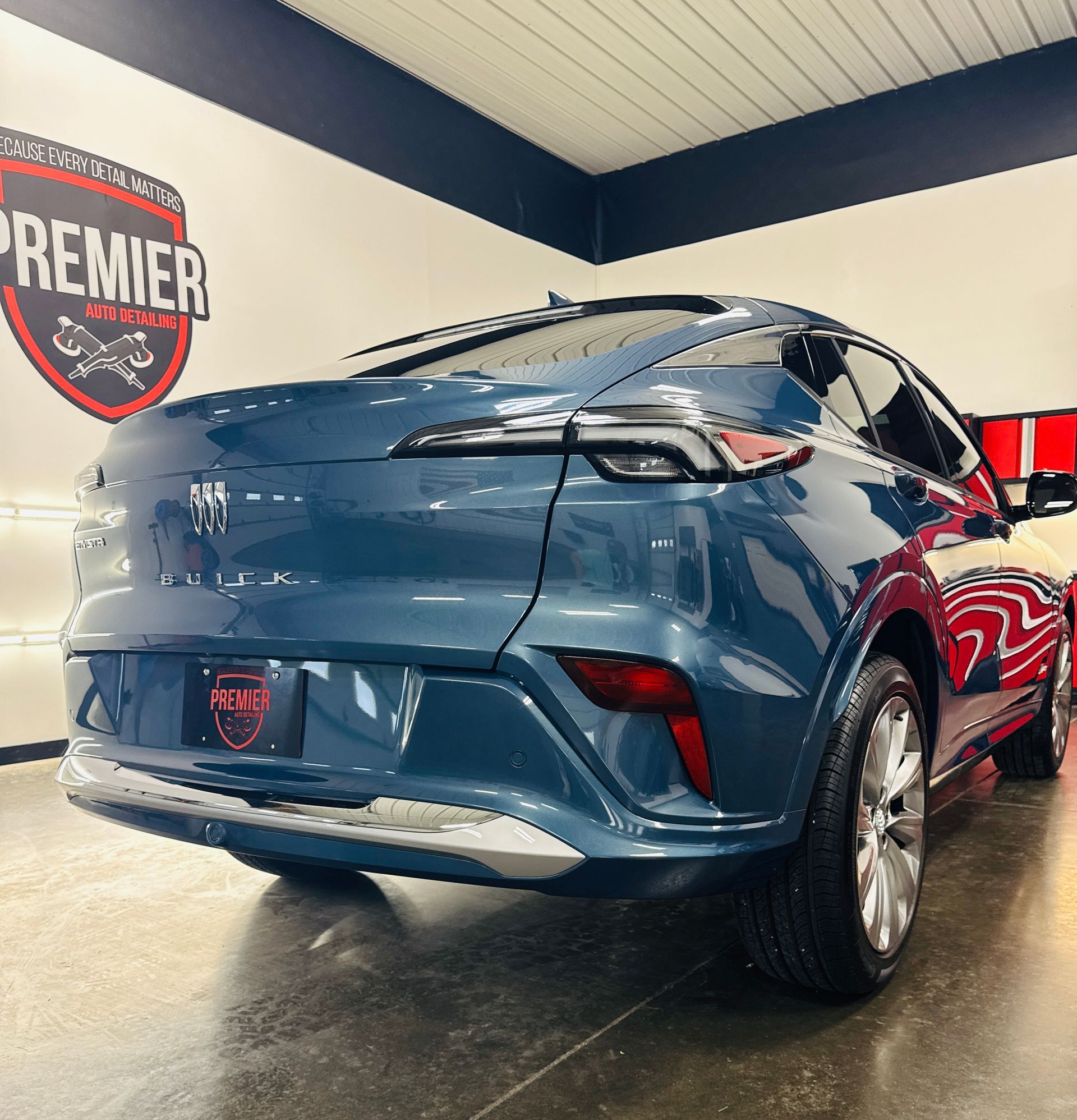 Blue SUV parked inside a detailing shop, viewed from the rear. Shiny paint, chrome accents.