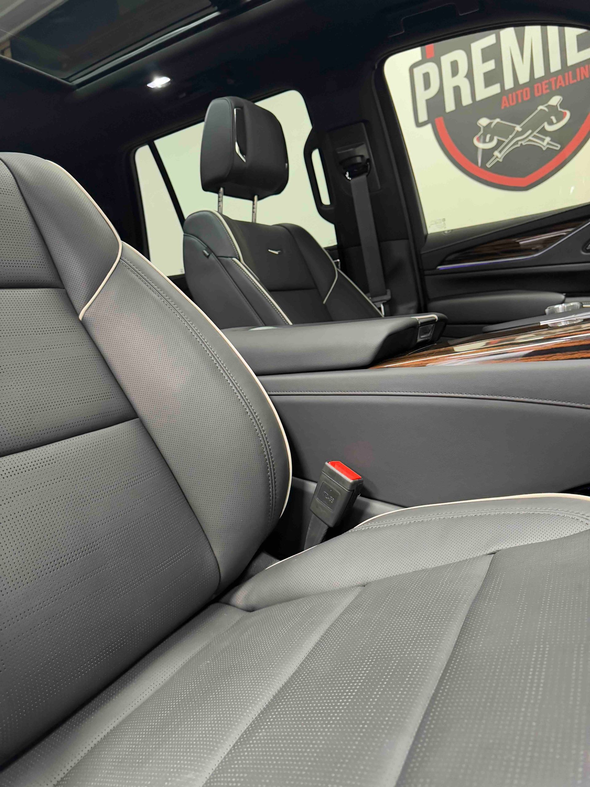 Interior of a luxury car with black and gray leather seats. A logo is visible on the window.
