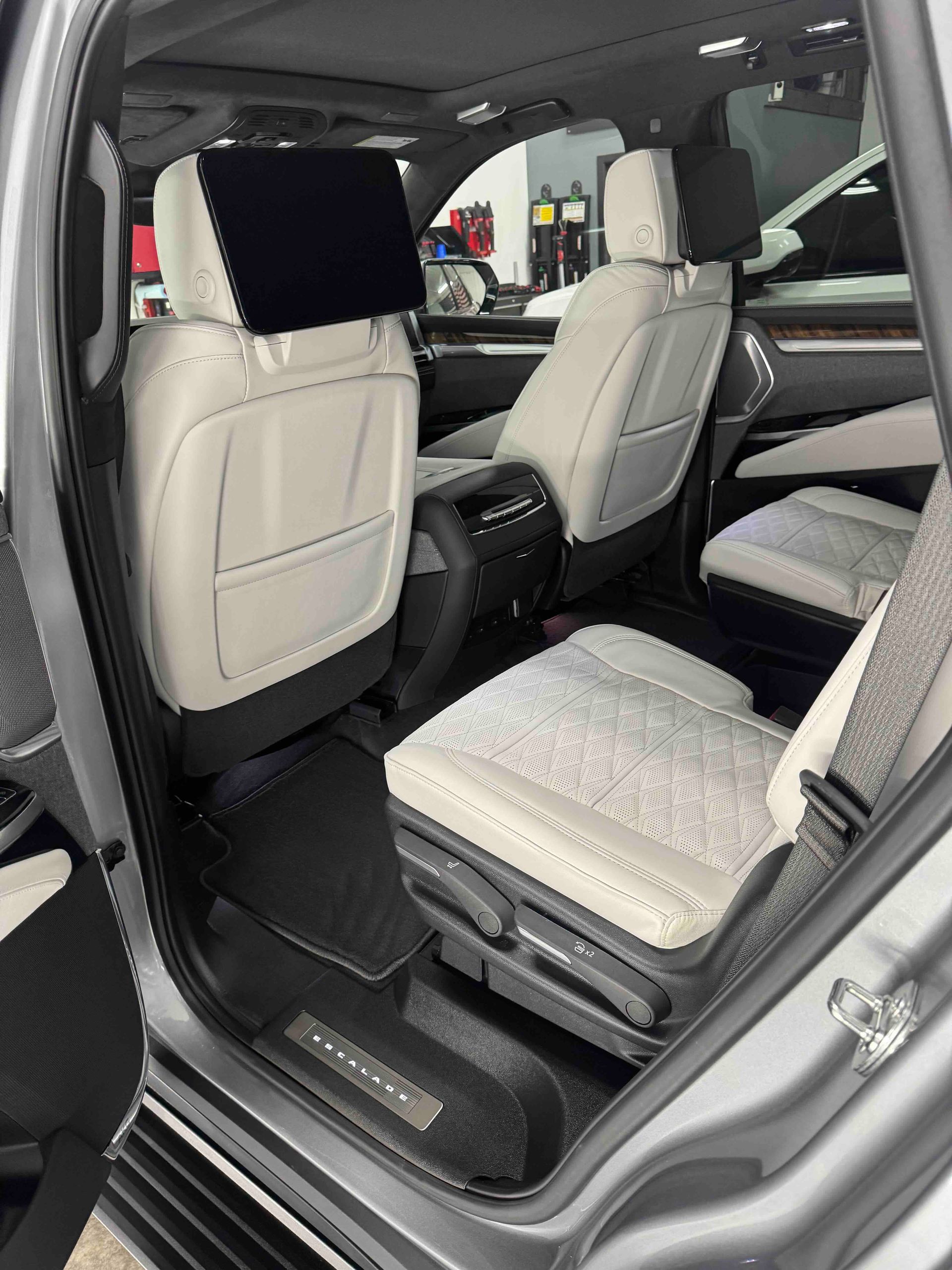 Gray vehicle interior with white leather seats and a rear-seat entertainment screen.