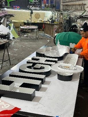A man is working on a large sign in a workshop.