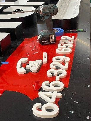 A drill is sitting on a table next to a sign that says ' call us ' on it.