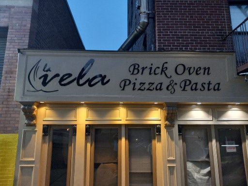 A sign for vela brick oven pizza and pasta